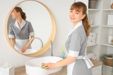 Genç oda hizmetçisi banyoyu temizliyor.