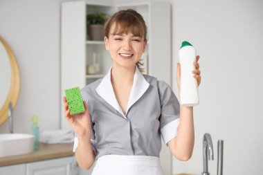 Banyoda temizlik süngeri ve deterjanı olan genç oda hizmetçisi.