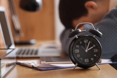 Ofisteki yorgun işadamlarının masasındaki çalar saat, yakın plan.