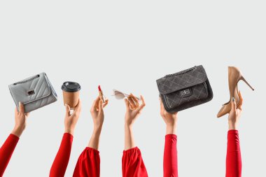 Şık kadın çantaları, aksesuarları ve gri arka planda bir fincan kahvesi olan kadın elleri.