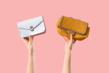 Pembe arka planda farklı tarz kadın çantaları olan kadın elleri.