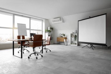 Ekran tahtası, masa ve koltukları olan geniş konferans salonunun içi