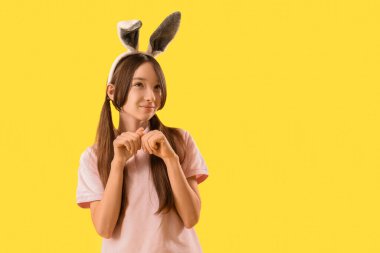 Sarı arka planda Paskalya tavşanı kulakları olan sevimli küçük bir kız.