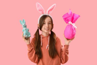 Paskalya tavşanı kulaklı, sevimli küçük kız, pembe arka planda hediye ve oyuncak tavşan.