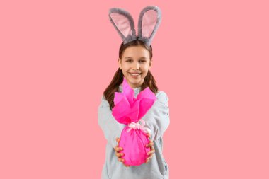 Paskalya tavşanı kulakları ve pembe arka planı olan sevimli küçük bir kız.