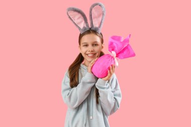 Paskalya tavşanı kulakları ve pembe arka planı olan sevimli küçük bir kız.