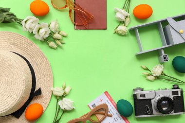 Yeşil arka planda Paskalya yumurtaları ve çiçeklerle yapılmış bir çerçeve. Tatil seyahati kompozisyonu