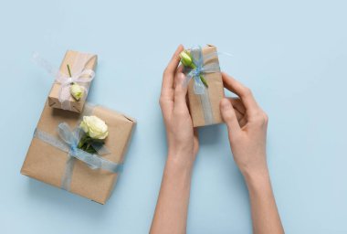 Hediye kutularıyla kadın elleri ve mavi arka planda güzel beyaz güller. Uluslararası Kadınlar Günü