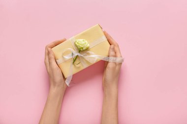 Pembe arka planda güzel beyaz güllü hediye kutusu olan kadın elleri. Uluslararası Kadınlar Günü