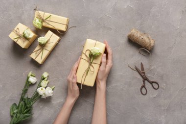 Hediye kutularıyla kadın elleri ve gri arka planda güzel beyaz güller. Uluslararası Kadınlar Günü