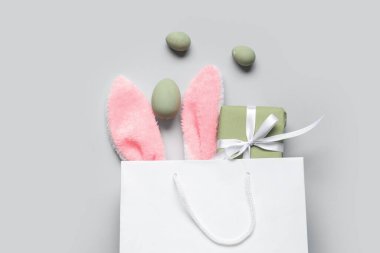 Tüylü tavşan kulaklı alışveriş torbası, hediye kutusu ve beyaz arka planda Paskalya yumurtası.
