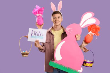 Tavşan kulaklı genç adam, yumurta ve leylak arka planda kağıttan tavşan. Paskalya Satışı