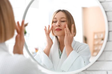 Tuvalette yüz geliştirme egzersizi yapan bir kadın.