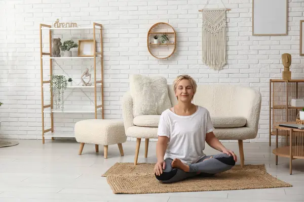 Reife Frau Meditiert Während Sie Hause Auf Dem Boden Sitzt — Stockfoto