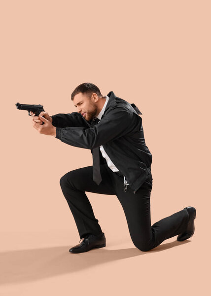 Male police officer with gun on beige background