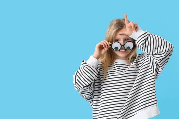 Niña Con Gafas Graciosas Mostrando Gesto Perdedor Sobre Fondo Azul —  Fotos de Stock