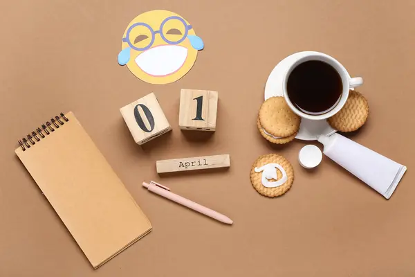 stock image Cookies with toothpaste, calendar and cup of tea on brown background. April Fools Day prank