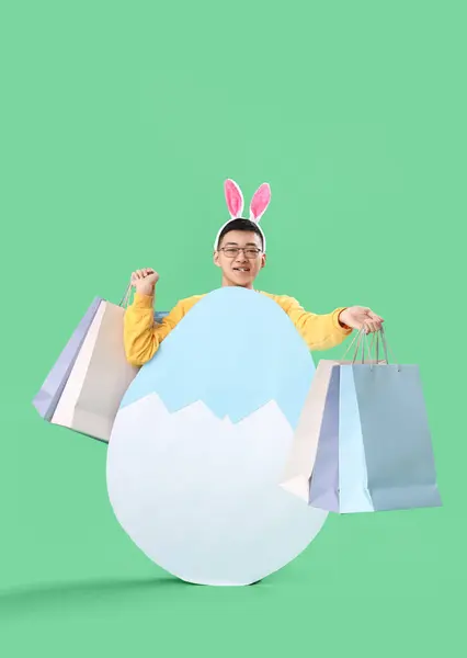 Junger Asiatischer Mann Hasenohren Mit Einkaufstaschen Und Papierei Auf Grünem — Stockfoto