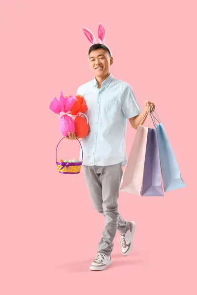 Junger Asiatischer Mann Hasenohren Mit Eiern Und Einkaufstaschen Auf Rosa — Stockfoto