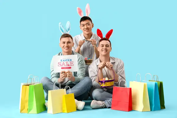 Junge Männer Hasenohren Mit Eiern Und Einkaufstüten Sitzen Auf Blauem — Stockfoto