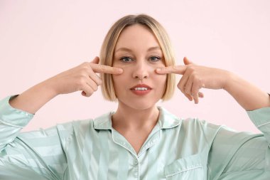 Pembe arka planda yüz geliştirme egzersizi yapan kadın.