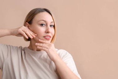 Bej arka planda yüz geliştirme egzersizi yapan kadın