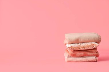 Pembe arka planda katlanmış sıcak ekose ve yastık yığını