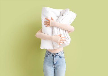 Yeşil arka planda beyaz katlanmış yumuşak battaniyeli kadın.