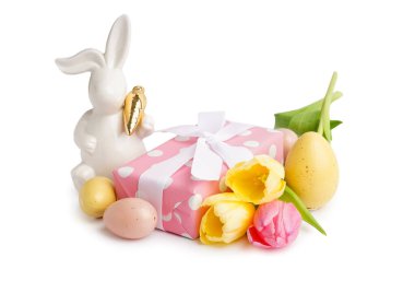 Paskalya tavşanı figürü, boyanmış yumurtalar, laleler ve beyaz arka planda hediye.