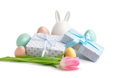 Paskalya yumurtaları, tavşan figürü, lale ve beyaz arka planda hediyeler.
