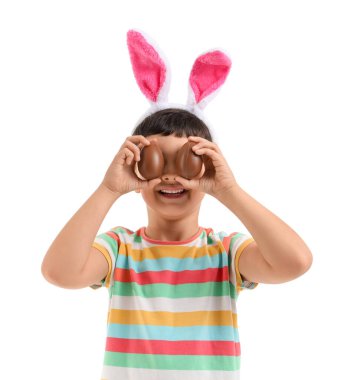 Beyaz arka planda Paskalya için çikolata yumurtalı tavşan kulaklı şirin bir çocuk.