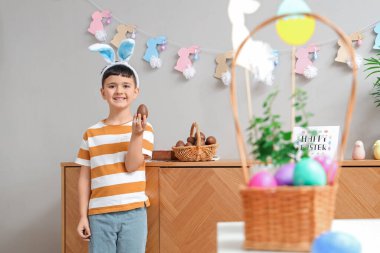 Paskalya evi için dekore edilmiş çikolata yumurtası sepeti ile tavşan kulaklı şirin bir çocuk.