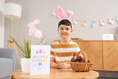 Paskalya evi için dekore edilmiş çikolata yumurtası sepeti ile tavşan kulaklı şirin bir çocuk.