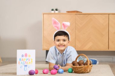 Tavşan kulaklı şirin bir çocuk. Evde paskalya için bir sepet çikolatalı yumurta ve neşeli kartpostallı.