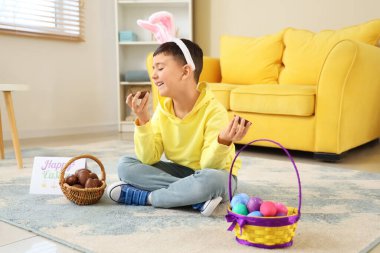 Tavşan kulaklı şirin çocuk Paskalya 'da evde çikolatalı yumurta yiyor.