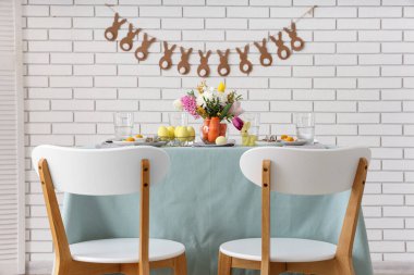 Paskalya için çok güzel bir masa. Beyaz tuğla duvarın yanında havuç ve çiçeklerle süslenmiş.