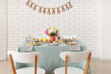 Paskalya için çok güzel bir masa. Beyaz tuğla duvarın yanında havuç ve çiçeklerle süslenmiş.