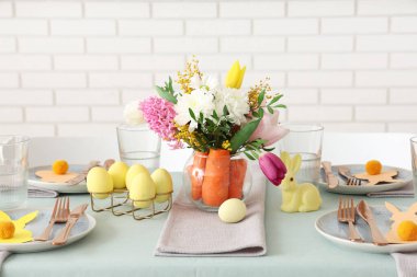 Paskalya için çok güzel bir masa. Beyaz tuğla duvarın yanında havuç ve çiçeklerle süslenmiş.