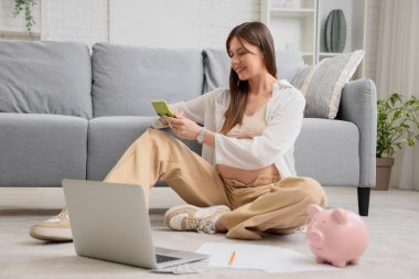 Evde hesap makinesi kullanan hamile bir kadın. Annelik Faydası konsepti