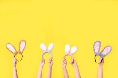 Sarı arka planda Paskalya tavşanı kulaklığı tutan kadın eller.