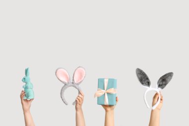 Paskalya tavşanı kulaklıklı hediye kutulu kadın elleri ve beyaz arka planda oyuncak tavşan.
