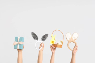 Paskalya tavşanı kulaklıklı, hediye kutusu ve beyaz arka planda sepeti olan kadın elleri.