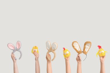 Paskalya tavşanı kulaklığı tutan kadın eller ve beyaz arka planda oyuncak tavuklar.