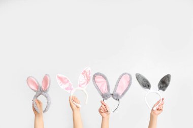 Beyaz arka planda Paskalya tavşanı kulaklığı tutan kadın eller.