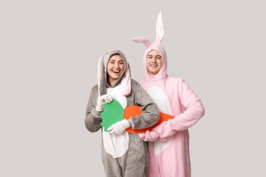 Gri arka planda kağıt havuç olan tavşan kostümlü güzel bir çift. Paskalya kutlaması