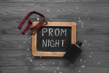 Tebeşir tahtası, metin PROM GECE, papyon ve parfüm şişesi gri ahşap arka planda