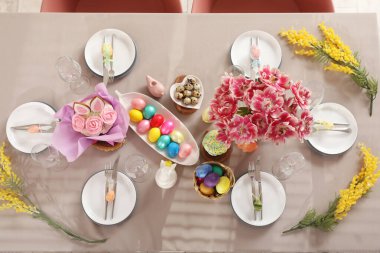 Mimoza çiçekleri, Paskalya pastası ve boyalı yumurtalarla süslü bir masa.