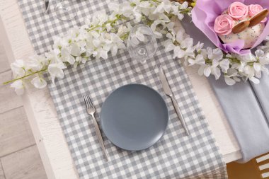 Çiçekler, paskalya pastaları ve boyalı yumurtalarla süslü bir masa.