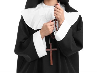 Beyaz arka planda tespih taşıyan genç bir rahibe, yakın plan.