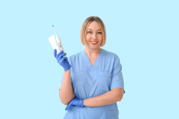 Vrouwelijke Tandarts Met Tandenborstel Plak Blauwe Achtergrond — Stockfoto